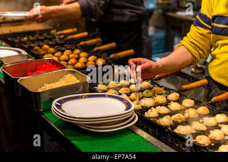 Préparer les chefs japonais et d'autres grignotines takoyaki à un décrochage, à Osaka au Japon. Banque D'Images