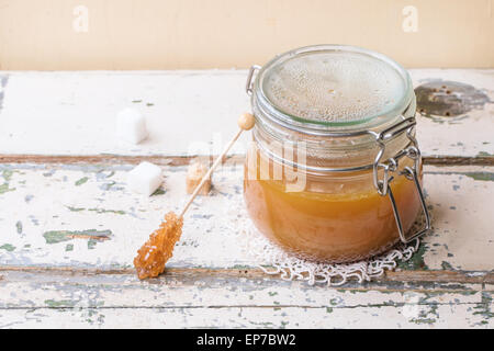 Pot de sauce au caramel fait maison, servi avec des morceaux de sucre sur la table en bois Banque D'Images