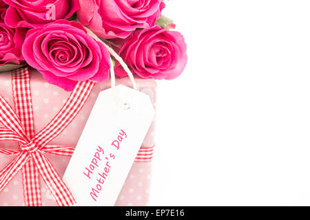 Close up d'un bouquet de roses roses à côté d'un cadeau rose avec une heureuse fête des mères carte sur un bac blanc Banque D'Images