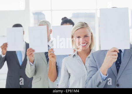 L'équipe d'affaires couvrant le visage avec du papier blanc à l'exception d'une femme Banque D'Images