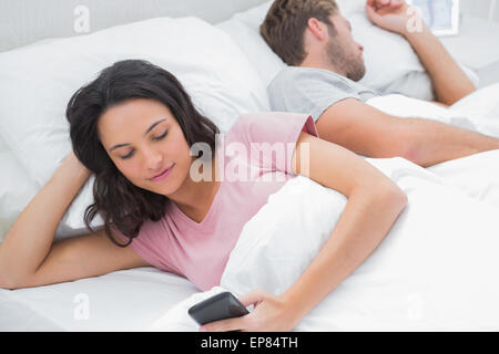 Femme en utilisant son téléphone quand son mari est en train de dormir Banque D'Images