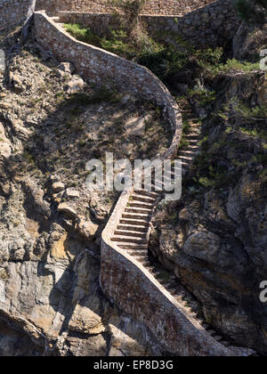 Un escalier en pierre descend la falaise de la Cami de Ronda. Un chemin de pierre menant à bord de l'eau attire les promeneurs Banque D'Images