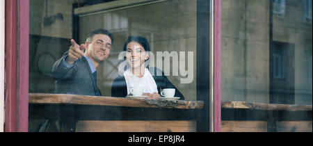 Happy businessman pointing sur quelque chose dans le café Banque D'Images