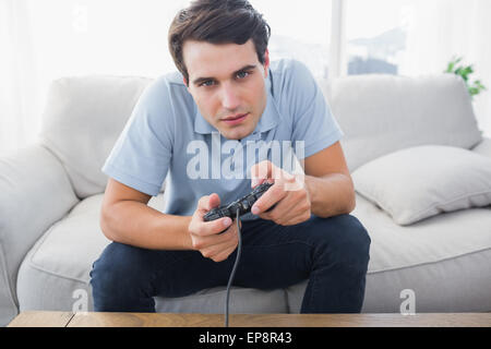 L'homme à jouer à des jeux vidéo pendant qu'il est assis sur un canapé Banque D'Images