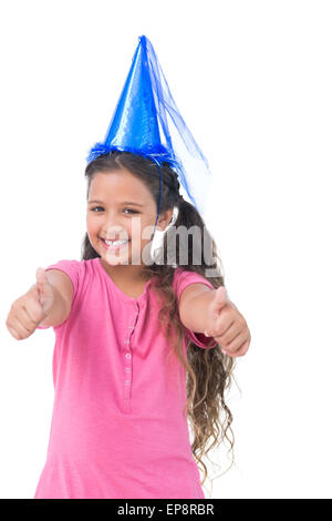 Smiling little girl wearing blue hat pour un parti et n'Thumbs up at camera Banque D'Images