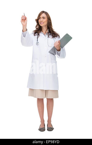 Brunette doctor holding clipboard and pointing at something Banque D'Images