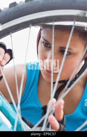 Athletic woman adjusting ses rayons sur la roue de vélo Banque D'Images