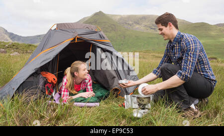 Smiling couple cooking outside on camping trip Banque D'Images