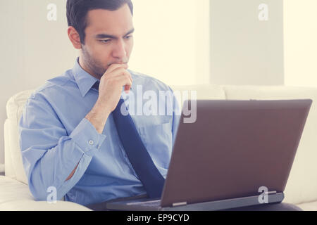 L'homme a souligné à l'aide d'un laptop sitting on a sofa
