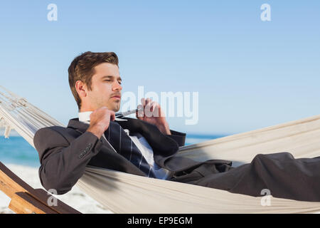 Young man lying in hamock taking off sa cravate Banque D'Images