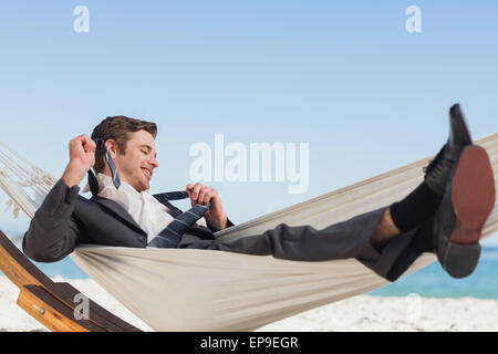 Smiling businessman lying in hamock taking off sa cravate Banque D'Images