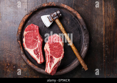 Forme de coeur la viande crue Ribeye Steak entrecote et viande cleaver sur fond sombre Banque D'Images