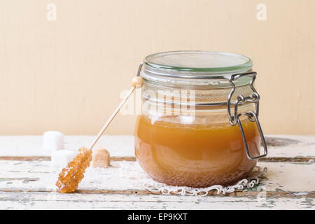 Pot de sauce au caramel fait maison, servi avec des morceaux de sucre sur la table en bois Banque D'Images