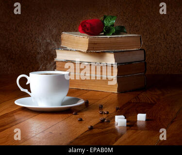 Tasse de café frais sur la table en bois et pile de livres à lire à la rose Banque D'Images