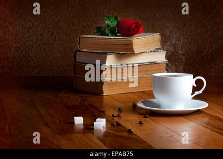 Tasse de café frais sur la table en bois et pile de livres à lire à la rose Banque D'Images