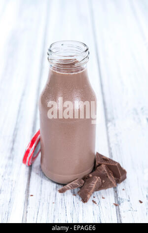 Le lait au chocolat dans une petite bouteille (sur fond lumineux en bois) Banque D'Images