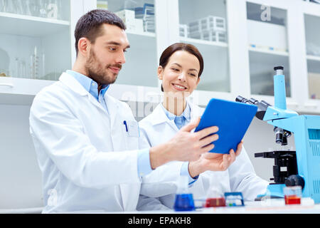 Les scientifiques avec tablet pc et microscope in lab Banque D'Images