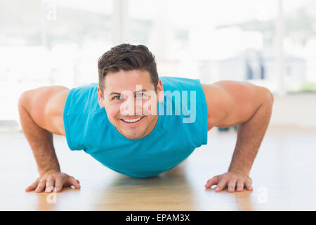 Portrait of a smiling young man doing push ups Banque D'Images