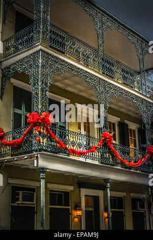 Le velours rouge Maison de festons pendent à la riche en fer forgé créole français, French Quarter, New Orleans, LA Banque D'Images