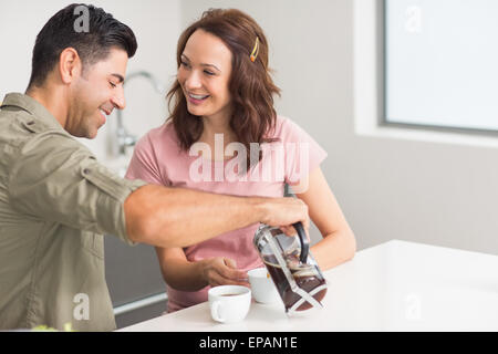 Happy man pouring plateau de coupe de womans in kitchen Banque D'Images