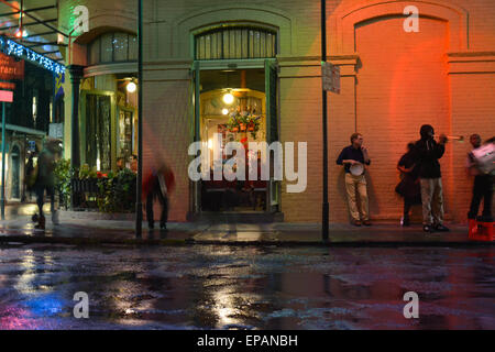 Des musiciens de rue en fin de soirée sur une pièce sombre Bourbon Street dans le quartier français sous la pluie à New Orleans, LA Banque D'Images