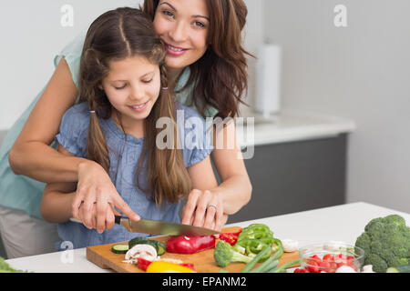 Smiling woman chopping vegetables in kitchen Banque D'Images