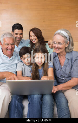 Famille élargie à l'aide d'un ordinateur portable sur un canapé dans la salle de séjour Banque D'Images