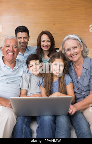 Famille élargie à l'aide d'un ordinateur portable sur un canapé dans la salle de séjour Banque D'Images