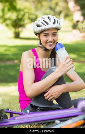 Fit woman dans helmet holding water bottle at park Banque D'Images