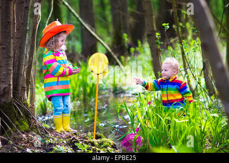 Les enfants jouent à l'extérieur. Deux enfants d'âge préscolaire avec grenouille capture net colorés. Petit garçon et fille la pêche dans une rivière de la forêt Banque D'Images