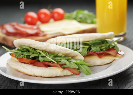 Deux sandwichs au jambon tomates et roquette dans le pain pita sur plaque, sur table en bois Banque D'Images