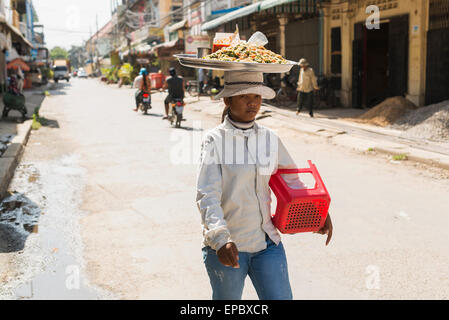 Une jeune femme transportant ses marchandises sur la tête dans le centre de Battambang, Cambodge ; Marché Banque D'Images