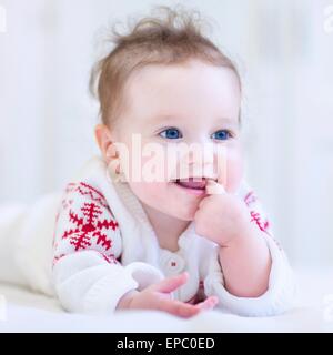 Gentil petit bébé portant un chandail tricoté avec red Christmas ornament Banque D'Images