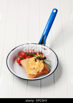 Oeufs brouillés sur toast et les tomates dans une casserole Banque D'Images