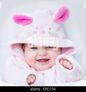 Happy Laughing baby girl sitting dans une poussette dans un lapin blanc robe-up Banque D'Images