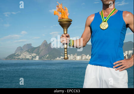 Médaille d'or de l'athlète brésilien avec torche sport permanent au-dessus de Rio de Janeiro Brésil skyline at Ipanema Beach Banque D'Images