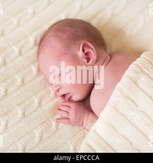 Adorable bébé nouveau-né dort sous une couverture en tricot chaud Banque D'Images