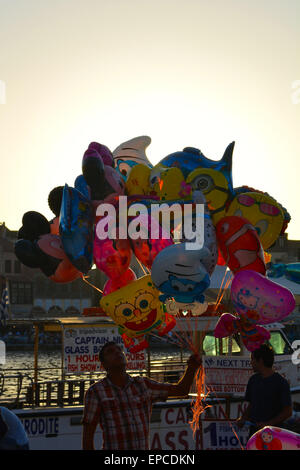 Un homme vend des ballons au coucher du soleil sur le port de La Canée, Crète, Grèce Banque D'Images