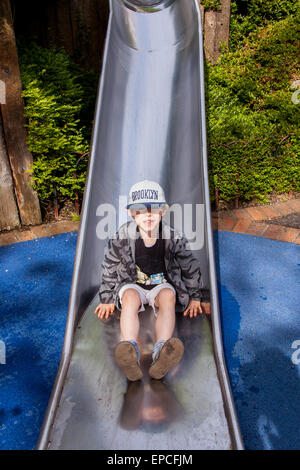 Six ans de descendre une metal slide à Legoland Windsor Resort, Londres, Angleterre, Royaume-Uni. Banque D'Images