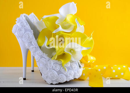 Thème jaune et blanc mariage floral suite nuptiale hautes chaussures de talon avec calla lilly bouquet sur shabby chic table en bois blanc et jaune Banque D'Images