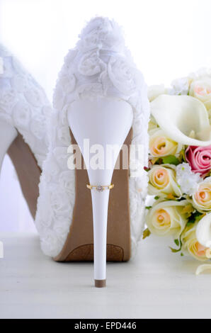 Jour de mariage concept avec joints toriques sur le talon du beau floral blanc chaussures stiletto suite nuptiale avec bouquet sur ta bois shabby chic blanc Banque D'Images