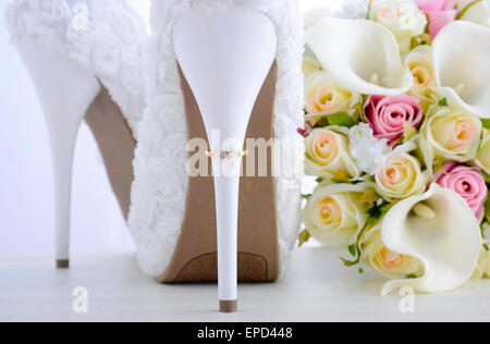 Jour de mariage concept avec joints toriques sur le talon du beau floral blanc chaussures stiletto suite nuptiale avec bouquet sur ta bois shabby chic blanc Banque D'Images