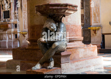 La figure accroupie sous le bénitier dans l'église de Santa Anastasia a été sculpté par Paolo Orefice. Il est connu comme "Pasquino" Banque D'Images