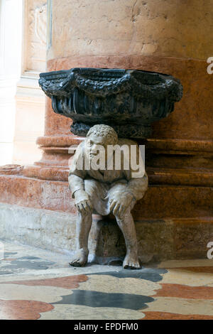 La figure accroupie sous le bénitier dans l'église de Santa Anastasia a été sculpté par Paolo Orefice. Il est connu comme "Pasquino" Banque D'Images