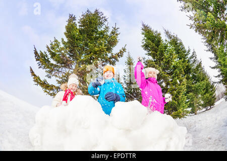 Filles et garçon jouant le jeu des boules de neige dans la forêt Banque D'Images