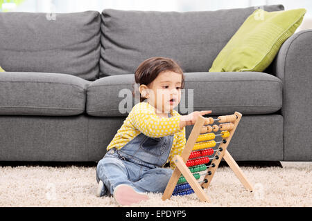 Jolie petite fille assise sur le plancher à la maison et jouer avec un boulier Banque D'Images