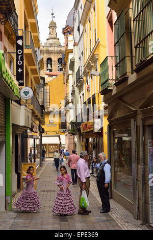 Deux filles en robes de flamenco dans la calle de la alcaiceria loza avec clocher à côté de l'église du sauveur Séville Espagne Banque D'Images