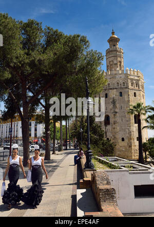 Deux jeunes femmes en robes de flamenco à marcher le long de l'Avenue Christophe Colomb à Torre del Oro, Séville Banque D'Images