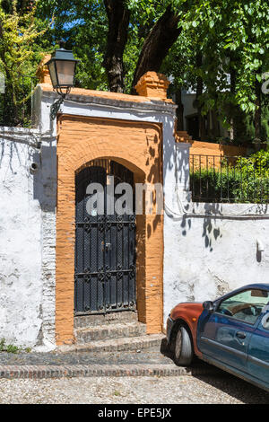 Peint en rouge brique, bordure en fer forgé entrée fermée dans un mur blanchi à la chaux sur une journée ensoleillée à Grenade, Andalousie, Espagne du sud Banque D'Images