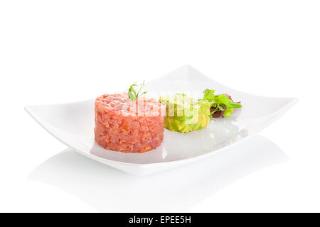 Délicieux steak tartare de thon à l'avocat trempette et salade verte fraîche sur la plaque sur fond blanc. Des restaurants raffinés. Banque D'Images